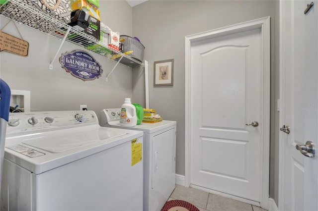 laundry area with independent washer and dryer and light tile patterned floors