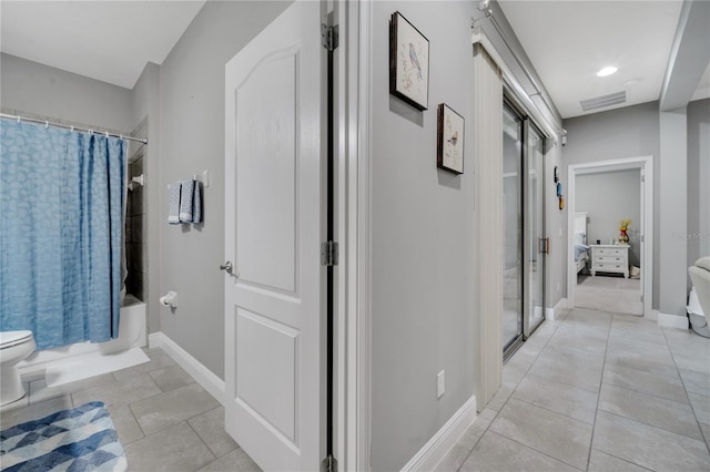 interior space featuring tile patterned flooring, toilet, and shower / tub combo with curtain