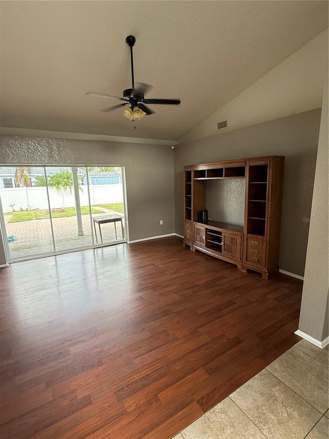 unfurnished living room with ceiling fan, vaulted ceiling, and dark wood-type flooring