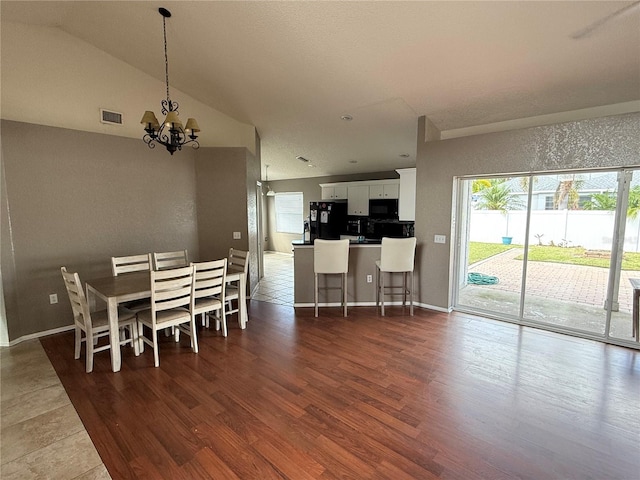 dining area with lofted ceiling, dark wood-type flooring, and an inviting chandelier