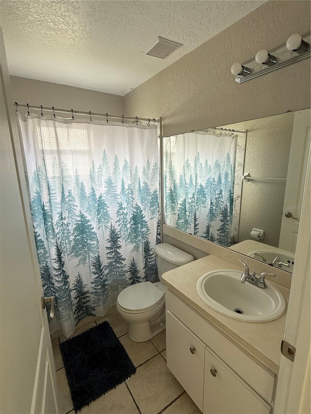 bathroom with toilet, vanity, tile patterned floors, and a textured ceiling