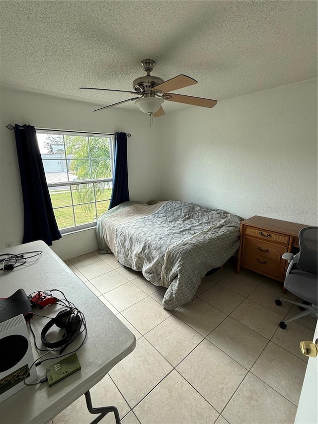 tiled bedroom featuring ceiling fan and a textured ceiling