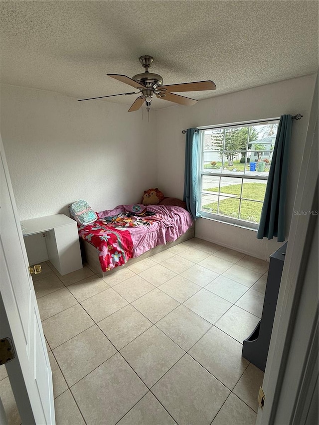 unfurnished bedroom featuring a textured ceiling, ceiling fan, and light tile patterned floors