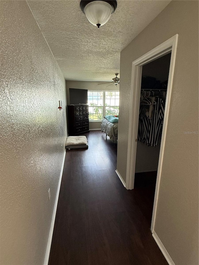 corridor with dark wood-type flooring and a textured ceiling