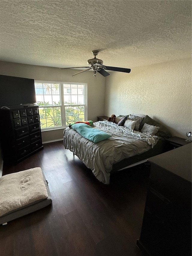 bedroom with ceiling fan, dark wood-type flooring, and a textured ceiling