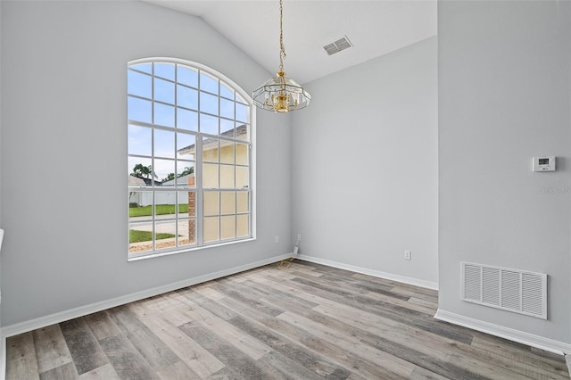 unfurnished room with lofted ceiling, hardwood / wood-style flooring, and a chandelier