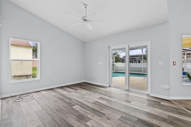 empty room with ceiling fan, high vaulted ceiling, and light hardwood / wood-style floors