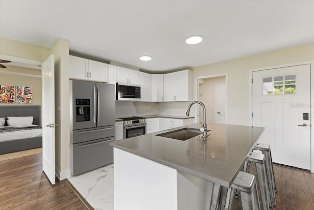 kitchen with hardwood / wood-style floors, stainless steel appliances, and white cabinets