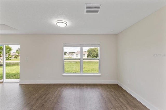 unfurnished room featuring a textured ceiling and dark hardwood / wood-style flooring