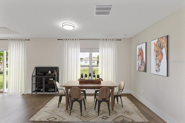 dining area with wood-type flooring and a textured ceiling