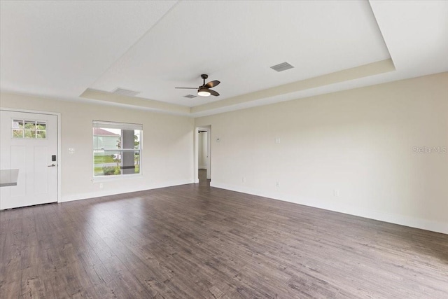 unfurnished living room with ceiling fan, hardwood / wood-style floors, and a tray ceiling