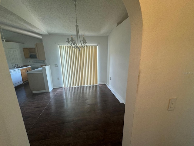 unfurnished dining area featuring a chandelier, sink, dark tile patterned flooring, and a textured ceiling