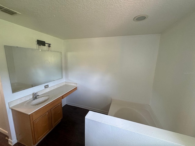 bathroom with a bathing tub, vanity, and a textured ceiling