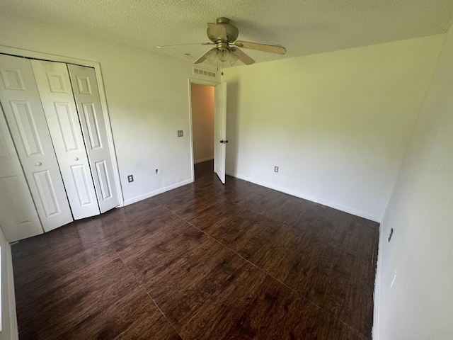 unfurnished bedroom featuring dark hardwood / wood-style flooring, a closet, a textured ceiling, and ceiling fan