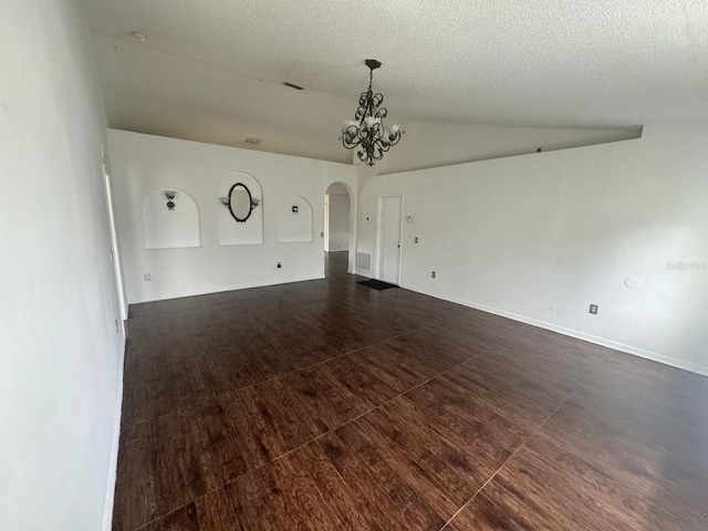 unfurnished room featuring an inviting chandelier, a textured ceiling, hardwood / wood-style flooring, and lofted ceiling