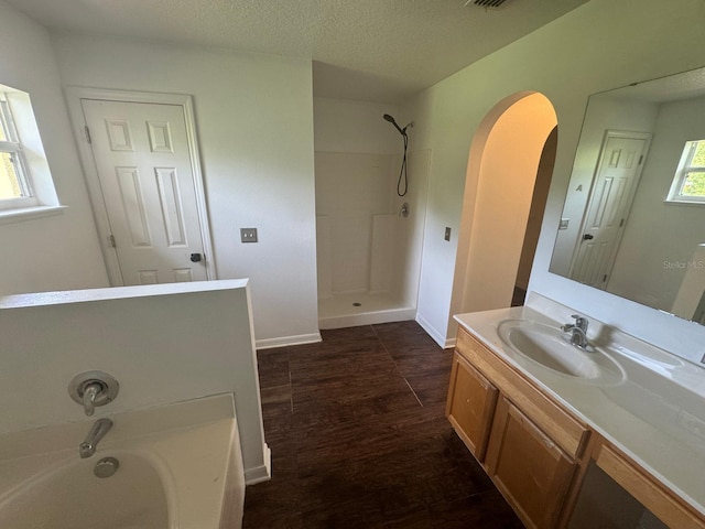 bathroom with hardwood / wood-style flooring, shower with separate bathtub, vanity, and a textured ceiling