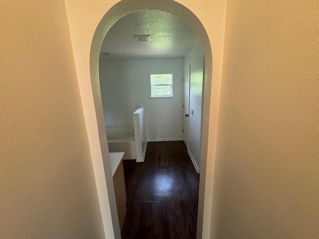 hallway with a textured ceiling and hardwood / wood-style floors