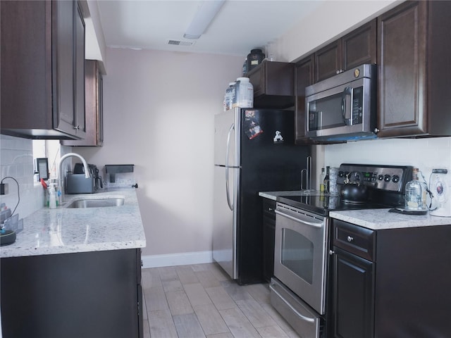 kitchen with stainless steel appliances, sink, backsplash, and light stone counters