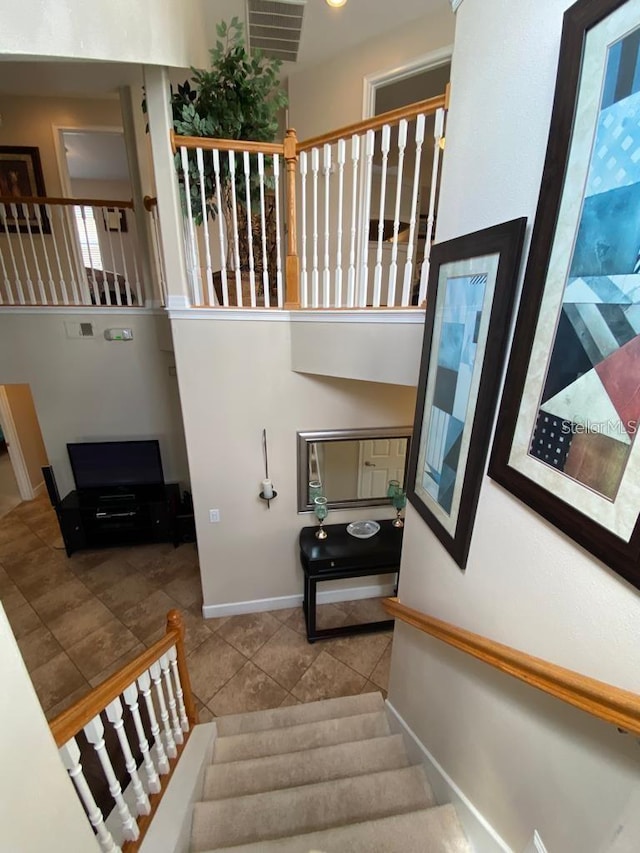 staircase with tile patterned floors and a high ceiling