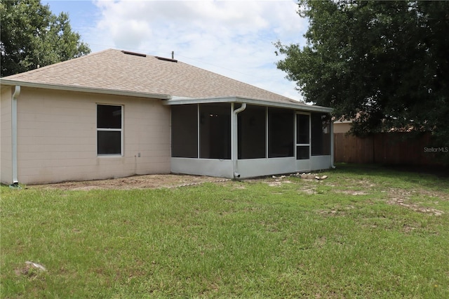 back of property with a sunroom and a lawn