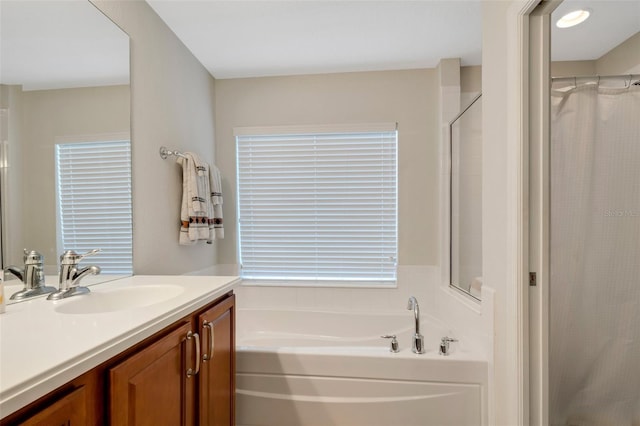 bathroom featuring plus walk in shower, a wealth of natural light, and vanity