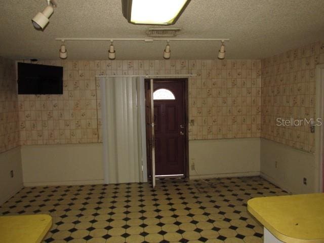 foyer with rail lighting and a textured ceiling