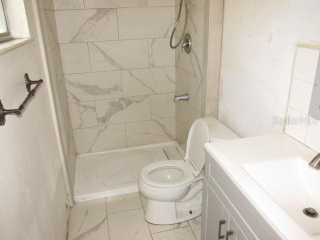 bathroom with vanity, toilet, and tiled shower