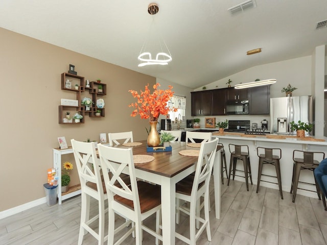 dining room featuring light hardwood / wood-style flooring, lofted ceiling, and an inviting chandelier