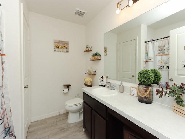 bathroom featuring wood-type flooring, vanity, and toilet