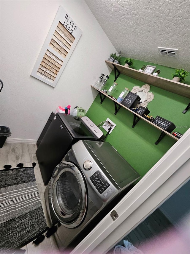 details featuring a textured ceiling, washing machine and dryer, and hardwood / wood-style flooring