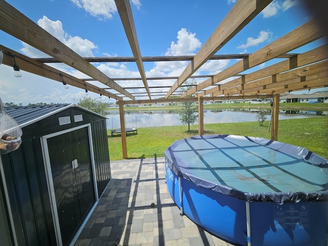 view of patio featuring a pergola, a water view, and a shed