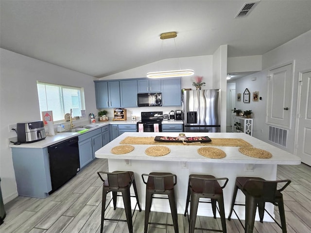 kitchen featuring blue cabinets, lofted ceiling, sink, light hardwood / wood-style flooring, and black appliances