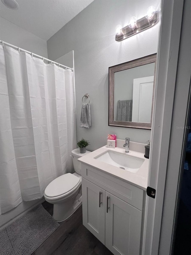 bathroom with toilet, a textured ceiling, hardwood / wood-style floors, and vanity