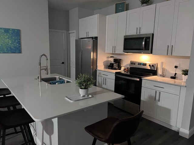 kitchen featuring sink, white cabinets, stainless steel appliances, and a breakfast bar area