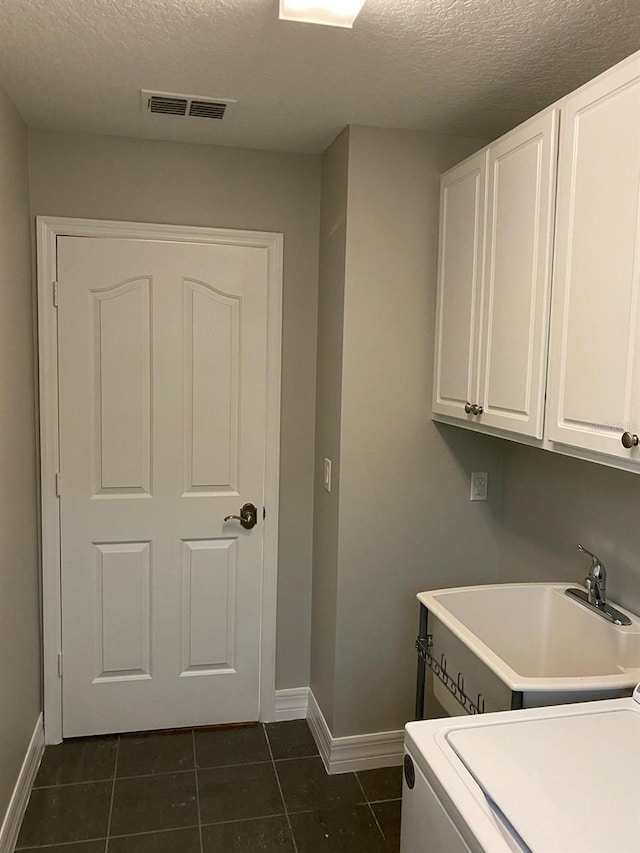 washroom with cabinets, sink, dark tile patterned flooring, and a textured ceiling