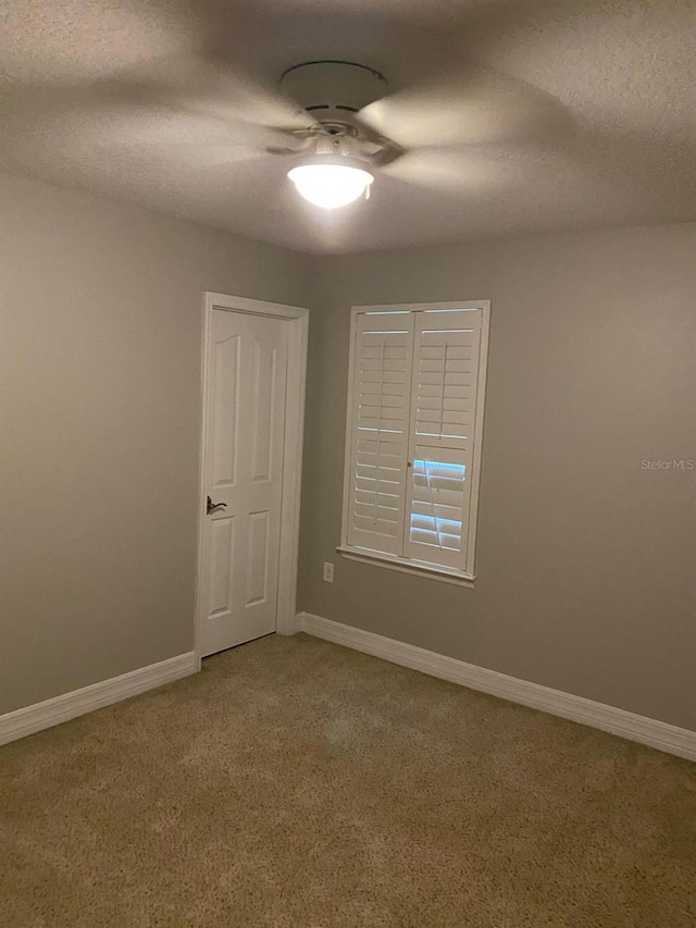 carpeted spare room featuring a textured ceiling and ceiling fan