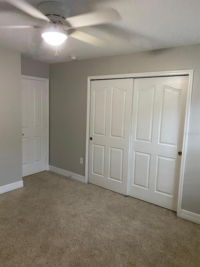 unfurnished bedroom with ceiling fan, light colored carpet, and a closet