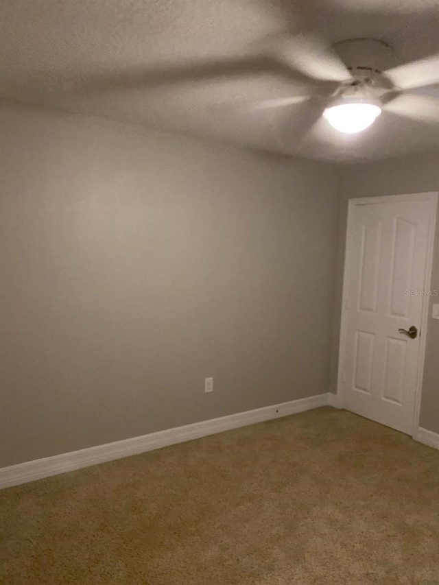 carpeted spare room with a textured ceiling and ceiling fan