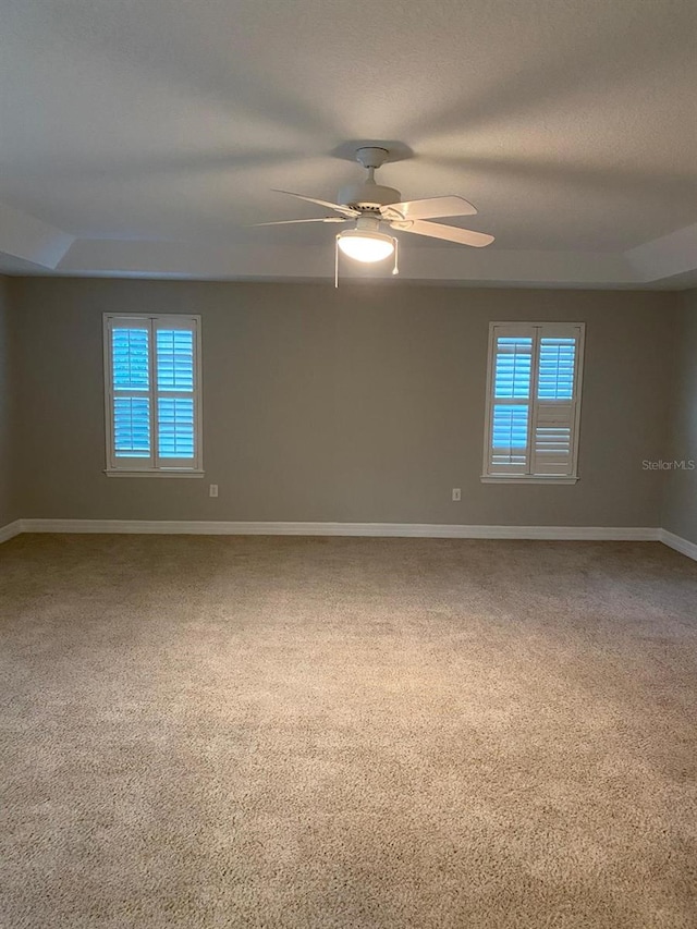 carpeted empty room featuring ceiling fan and a tray ceiling