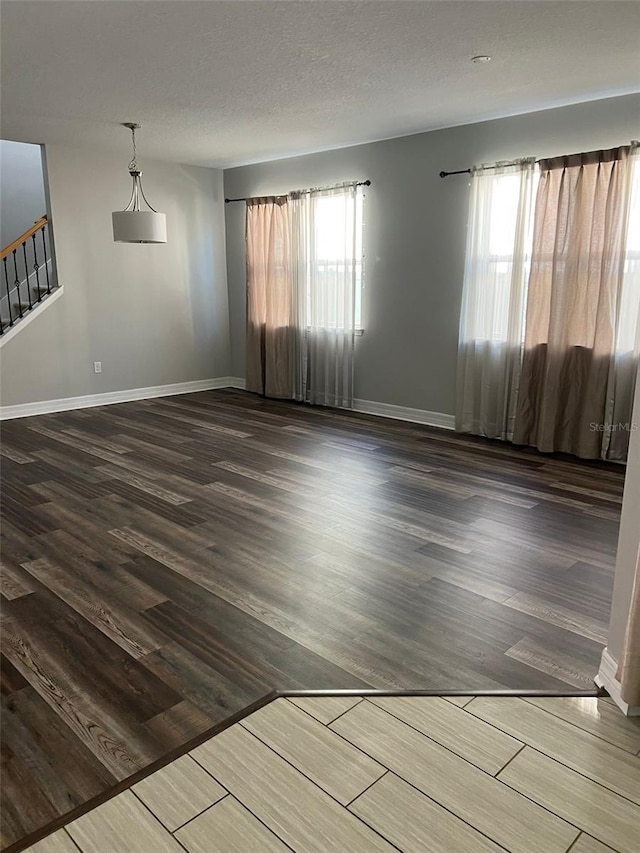 unfurnished room with dark hardwood / wood-style flooring and a textured ceiling