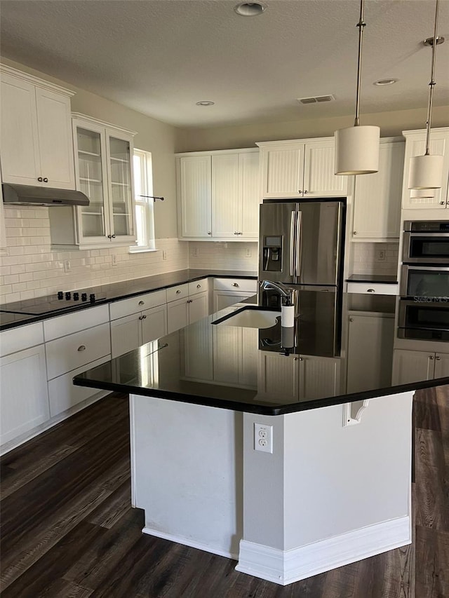 kitchen with hanging light fixtures, an island with sink, appliances with stainless steel finishes, and white cabinets