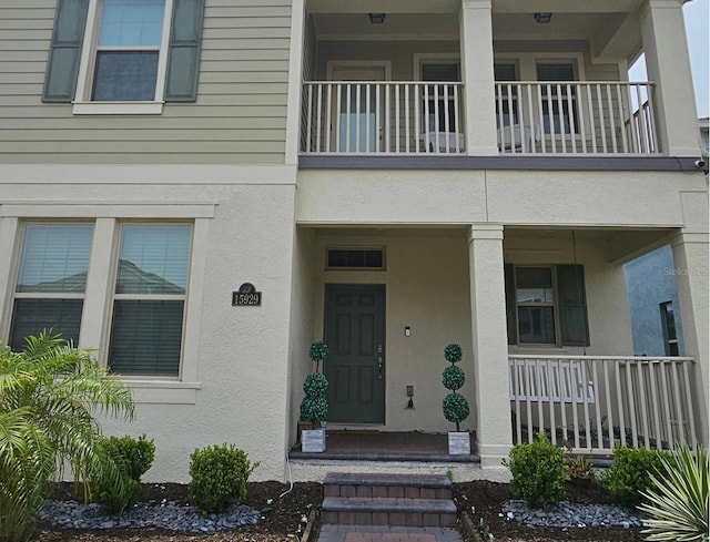 doorway to property featuring a balcony and stucco siding