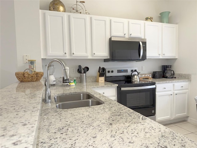 kitchen featuring sink, light tile patterned floors, appliances with stainless steel finishes, white cabinetry, and light stone counters