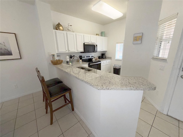 kitchen featuring a kitchen bar, sink, appliances with stainless steel finishes, kitchen peninsula, and white cabinets