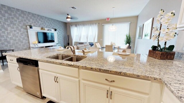 kitchen with sink, light stone counters, decorative light fixtures, dishwasher, and ceiling fan