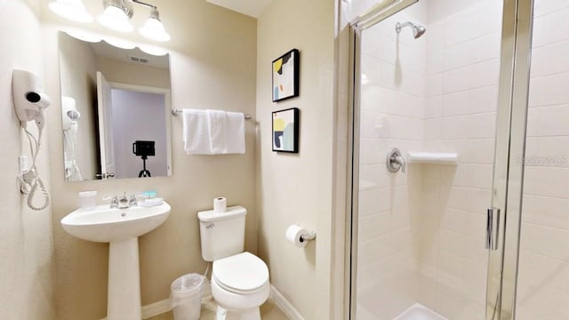 bathroom featuring a shower with shower door and toilet