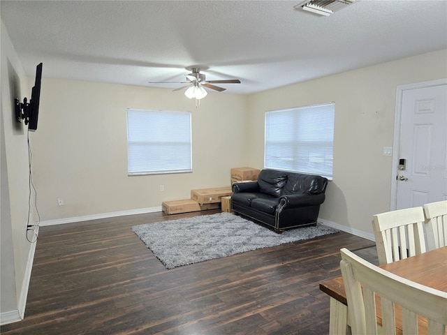 living room with ceiling fan, dark hardwood / wood-style flooring, a textured ceiling, and a wealth of natural light