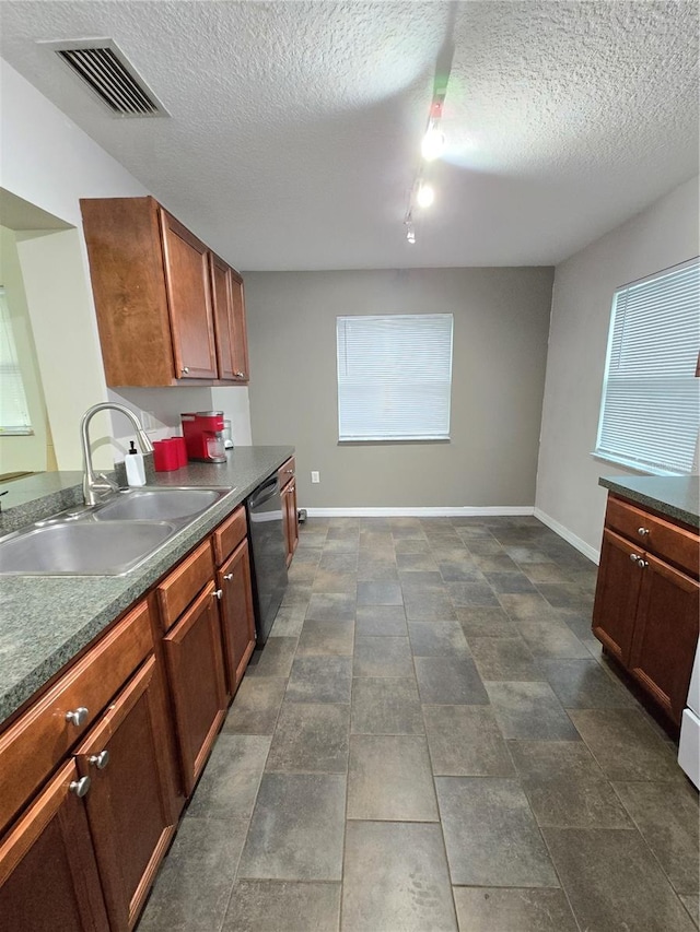 kitchen with sink, a textured ceiling, dishwasher, and dark tile patterned floors