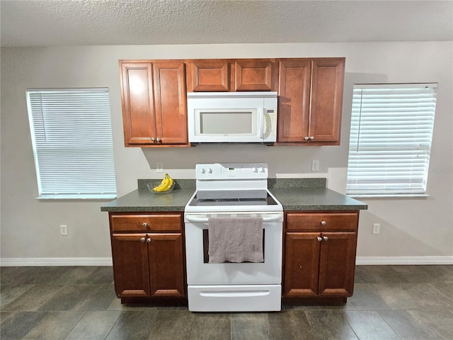 kitchen featuring dark tile patterned flooring, white appliances, and a textured ceiling