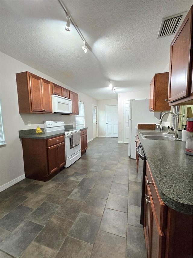 kitchen with sink, track lighting, a textured ceiling, and white appliances